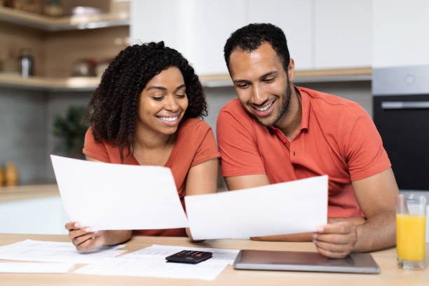 istock Cheerful millennial black lady and guy in red t-shirts work with documents, check bills, calculate profit in kitchen 1473500849