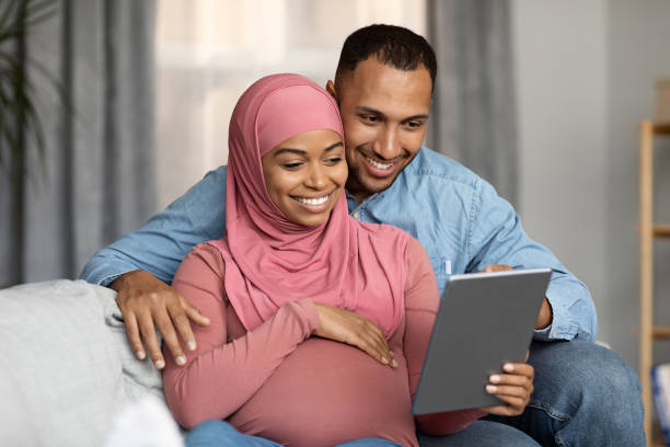 istock Happy Pregnant Black Muslim Spouses Using Digital Tablet While Relaxing At Home 1473500959