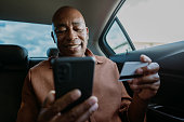 Portrait of passenger in car making credit card payment on smartphone