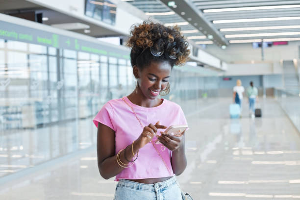 istock Woman using smart phone at airport 1473502347