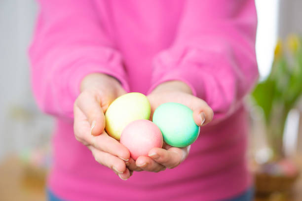 Close up of colorful homemade Easter eggs. Female hands holding three colored Easter eggs. Happy Easter. High quality photo.