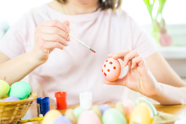 istock Close up of female hands holding an Easter egg a paintbrush. 1473503610