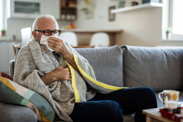 istock A senior Caucasian man is lying in bed with a bad cold and is blowing his nose using a napkin. An older ill man with temperature is lying in his bed covered with a blanket. 1473505698