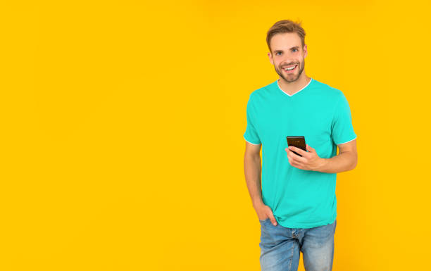 istock happy man in blue shirt on yellow background with copy space, communication 1473506441