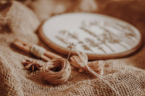 istock Embroidery kit. Hoop, floss threads and canvas on old vintage burlap background 1473506446