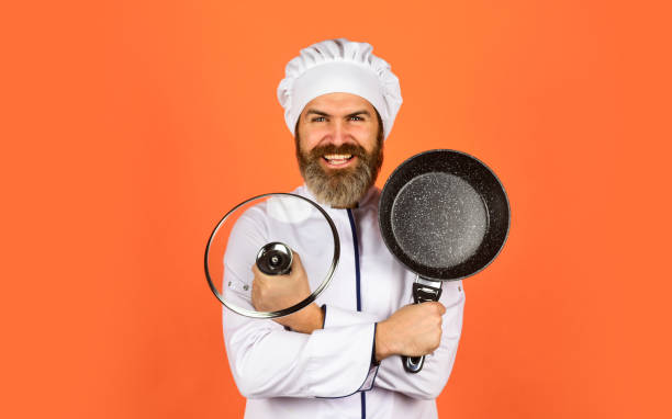 istock Enjoying cooking. Chef holds kitchenware. happy cook man hold frying pan. Chef in uniform cooking soup. restaurant kitchen. cooking lunch in kitchen. my profession. baker with saucepan pot. catering 1473506491