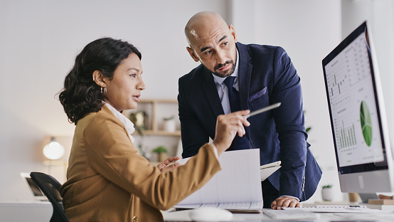 Business people, computer and analytics monitoring corporate statistics of graph or chart on screen at office. Businessman and woman in teamwork collaboration on company data or analysis on PC