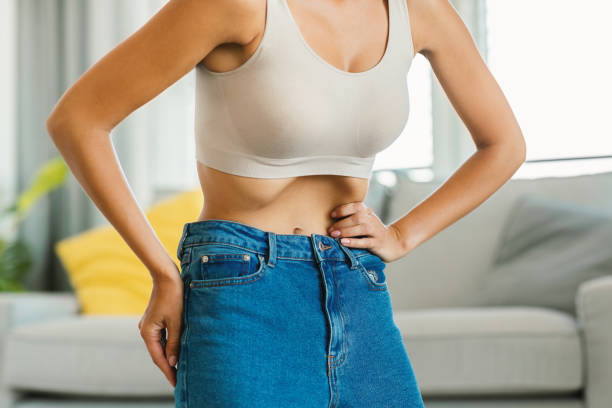 istock Unrecognizable young lady doing stomach vacuum exercise, flexing abdominal muscles, standing at home, closeup 1473509746