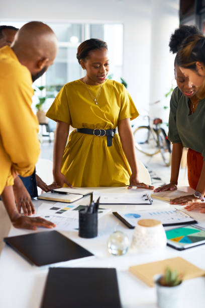 istock Black woman brainstorming with paperwork, teamwork and planning collaboration strategy in agency. Group of designers meeting with documents, business information feedback and graphs of data analysis 1473510285