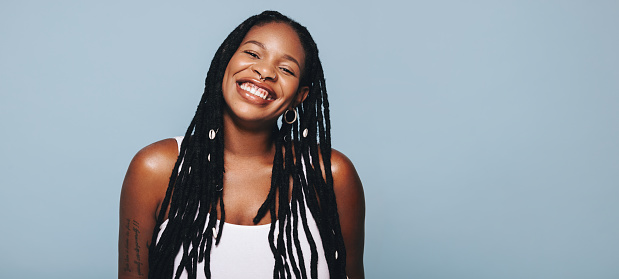 Retrato de una mujer africana con rastas sonriendo a la cámara en un estudio photo