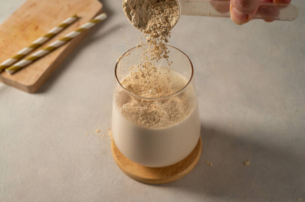 istock Pouring protein powder from scoop, in glass with milkshake. 1473512341