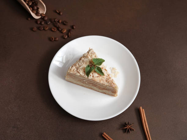 istock Layered Cake with cream Napoleon with mint on Brown background. A cinnamon stick, badyan, coffee beans on a brown background. Copy space 1473512351