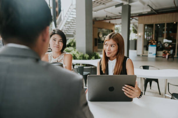 Small business meeting before presenting work to client Thai account manager woman working on her laptop while join outdoor meeting with her customer. south east asia choicepix stock pictures, royalty-free photos & images