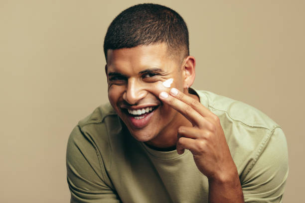 istock Happy young man using a beauty cream on his face to keep it healthy and fresh 1473513020