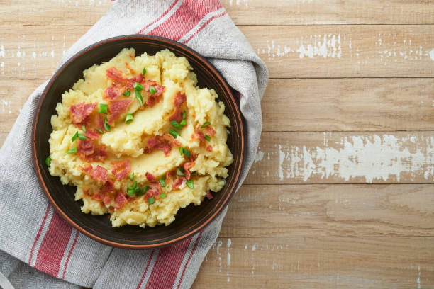 istock Mashed potatoes. Bacon mashed potatoes with green onion, pepper and cheddar cheese in bowl on old wooden backgrounds. Delicious creamy mashed potatoes. Top view. 1473513343