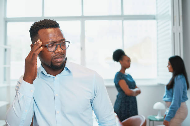 Black man looks upset while colleagues talk behind his back, office drama