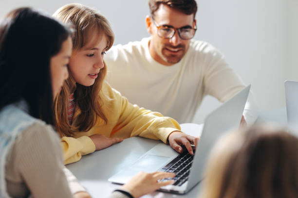 istock Digital literacy for young minds: Male tutor guiding young children in a computer class 1473513409
