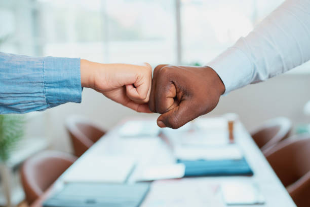 istock Two colleagues give fist bump over conference table, diversity celebrated 1473513441