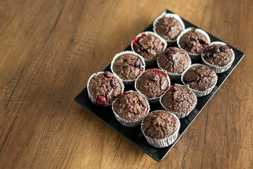 Group of delicious homemade muffins with berries on a wooden table.