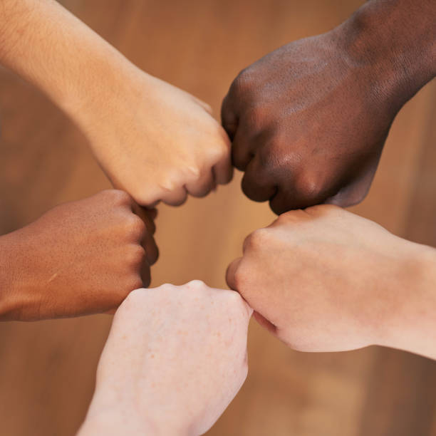 Circle of diverse hands, fists in circle, different skin colours unity teamwork stock photo