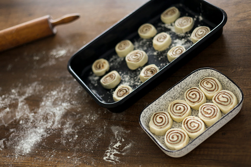 Preparing delicious homemade cinnamon buns on a wooden table.