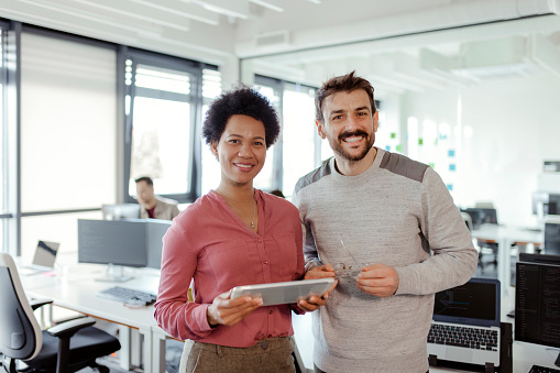 Portrait of two cheerful mixed race it professionals smiling at camera