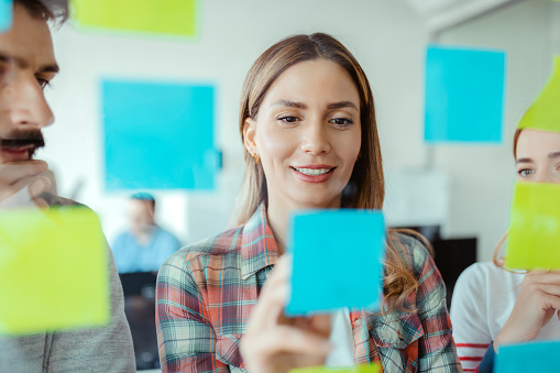 Shot of Coworkers Using Sticky Notes on a Glass Wall During a Meeting