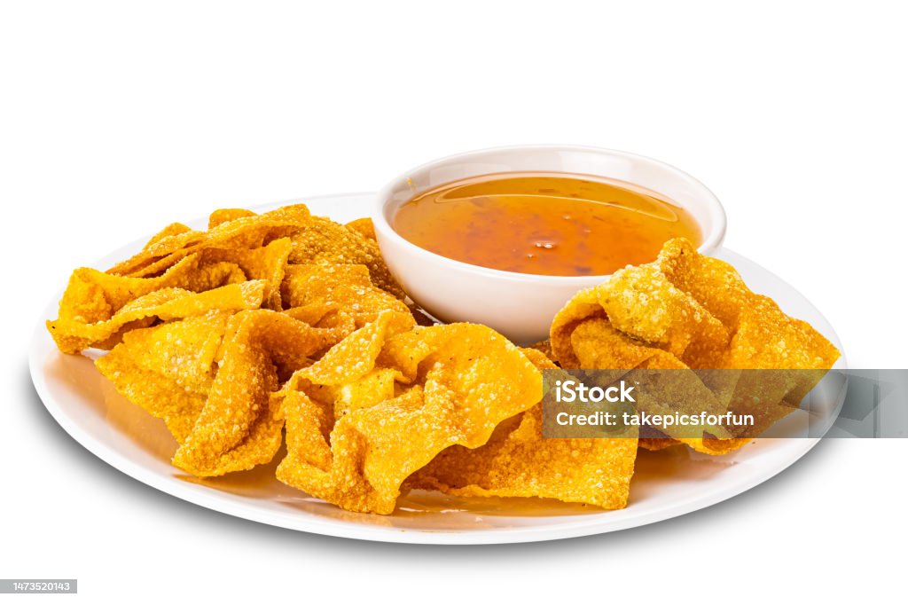 Pile of crispy delicious homemade deep fried wontons in white ceramic plate and sweet dipping sauce in white ceramic cup. Pile of crispy delicious homemade deep fried wontons in white ceramic plate and sweet dipping sauce in white ceramic cup isolated on white background with clipping path. Plate Stock Photo