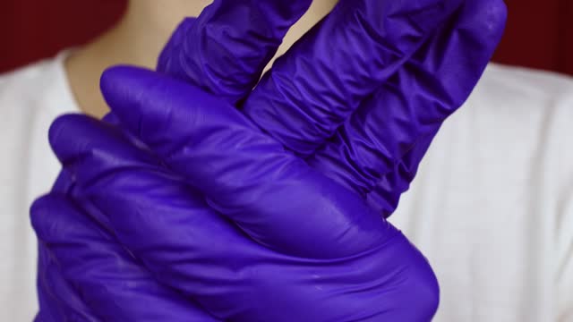 Woman putting blue protective nitrile gloves on hands close up