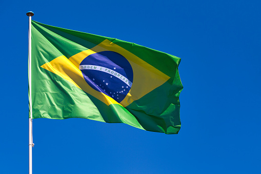Close-up on the flag of Brazil waving atop of its pole.