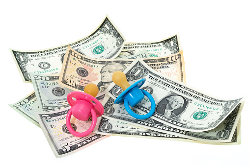 The ever increasing cost of infant childcare with USA currency  and baby pacifiers - white background.
