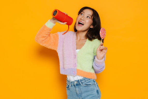 istock Asian young woman singing while posing with music column and lollipop 1473524200