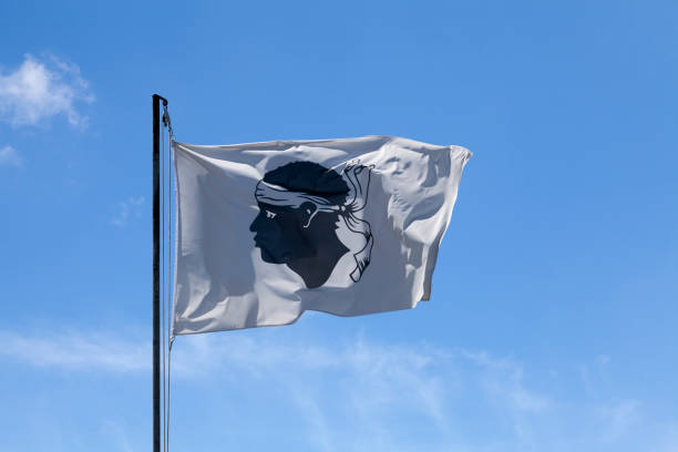 Corsican flag waving on its flagpole Corsican flag waving atop of its pole against a blue sky. corsican flag stock pictures, royalty-free photos & images