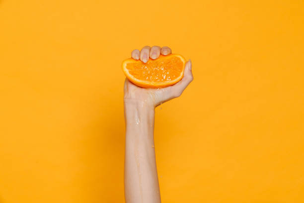 istock Female hand squeezing orange isolated 1473525177