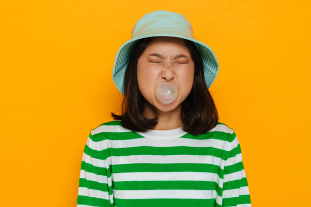 istock Asian young woman wearing panama blowing bubble while chewing gum 1473525385