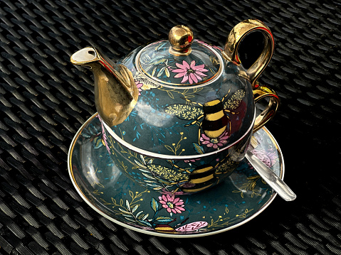 An ornate antique tea cup and teapot for one set.