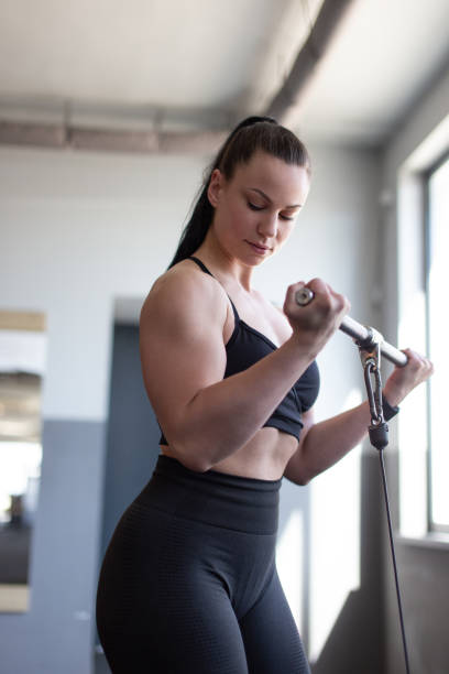 istock Woman doing bicep exercise in gym by bar 1473526033