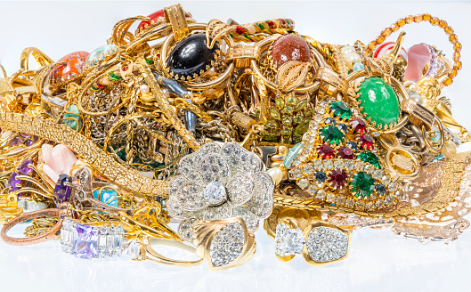 Horizontal shot of a cluster of colorful vintage jewelry on a white background.