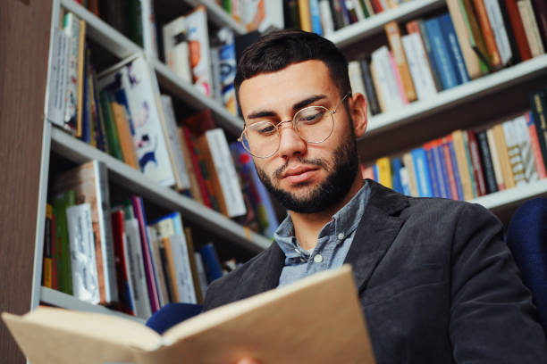 istock Intelligent man reading book in book shop 1473527458