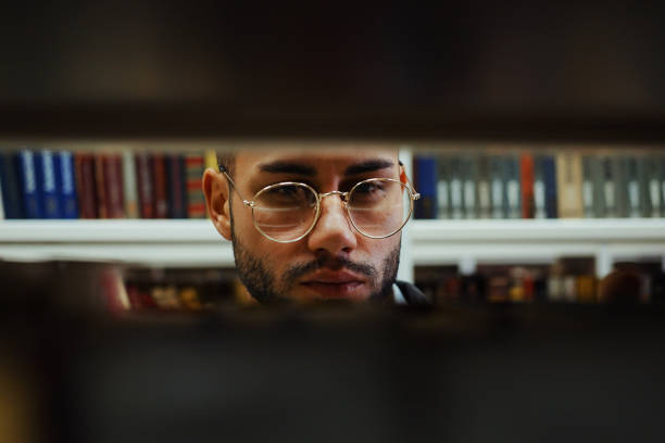 istock Man looking for book on shelves in library 1473527559
