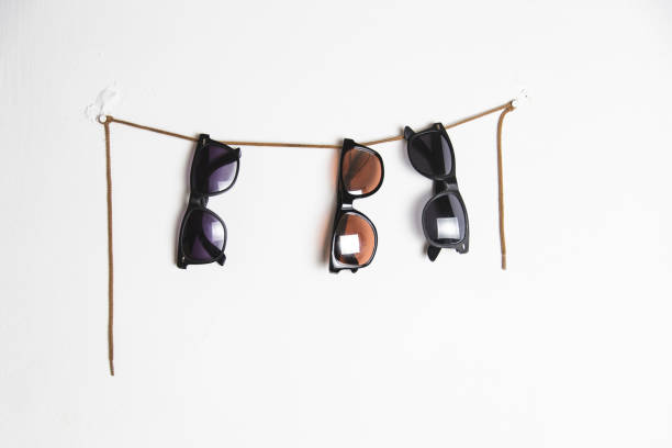 close up of sunglasses hanging on a white wall