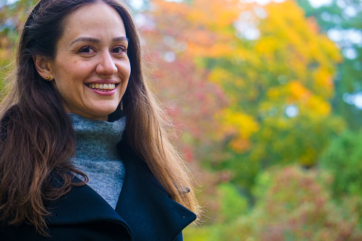 Portrait of smiling woman standing against trees during autumn