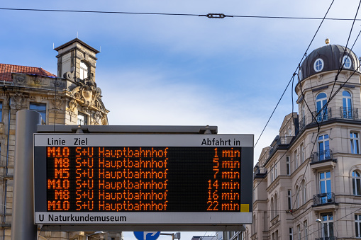 Close-Up Of Information Sign At Tram Station Against Buildings In City