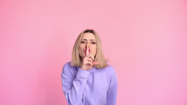Shocked woman doing a silence gesture in studio
