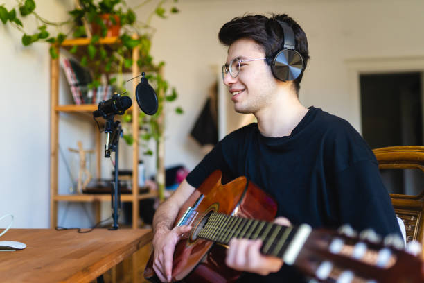 istock Young man playing guitar and recording at home 1473534639