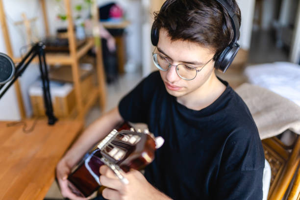 istock Young man playing guitar and recording at home 1473534756