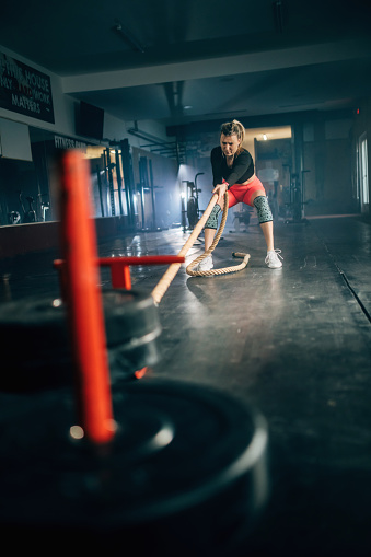 male athlete pushing and pulling  the sled in the gym