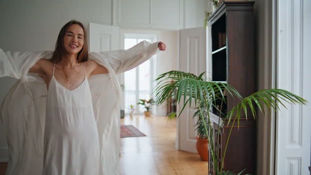 Active woman spinning at home interior. Smiling lady in silk pyjamas having fun