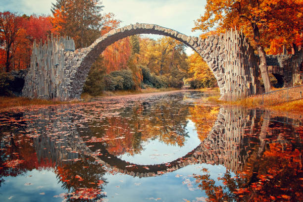 stone arch bridge kromlau made of basalt stones, in brightly colored autumn, called v or devils bridge - devils lake imagens e fotografias de stock