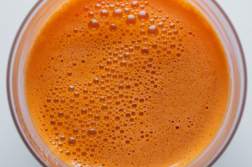 Glass of fresh carrot juice background, top view, close up. Healthy food concept